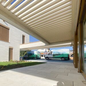 SKL 50 SKY Lamellendach an einem modernen Gebäude mit Thermogreen-Fahrzeugen im Hintergrund.