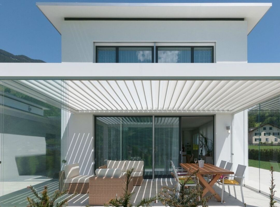 SKL 100 Lamellendach in Schattdorf, Uri – weisses Aluminiumdach mit Glaswänden und 300 kg/m² Schneelast, integriert in ein modernes Einfamilienhaus.