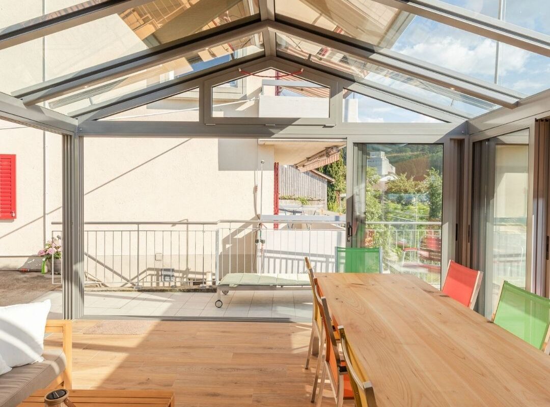 Wintergarten mit SGL1 Glasdach im Kanton Aargau, ausgestattet mit Beschattung und grossem Esstisch.