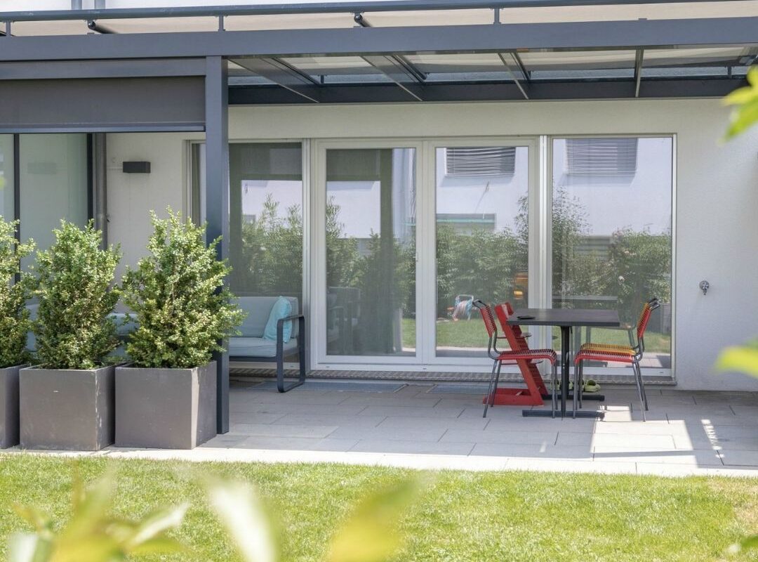 Modernes Glasdach in Ostermundigen, das den Sitzplatz vor dem Haus überdeckt und zuverlässigen Schutz mit einer Schneelast von bis zu 380 kg/m² bietet.