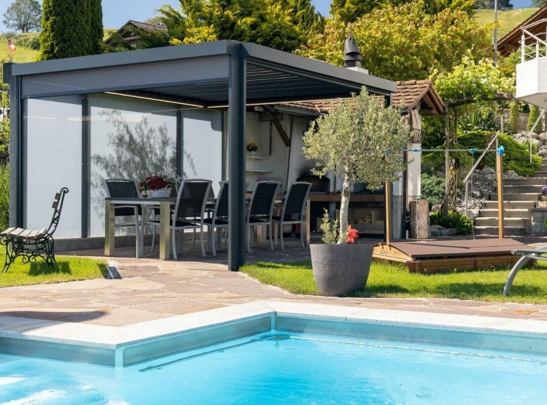 Lamellendach mit Glaswänden in Eggersriet St. Gallen, moderne Outdoor-Oase mit Essbereich und Pool.