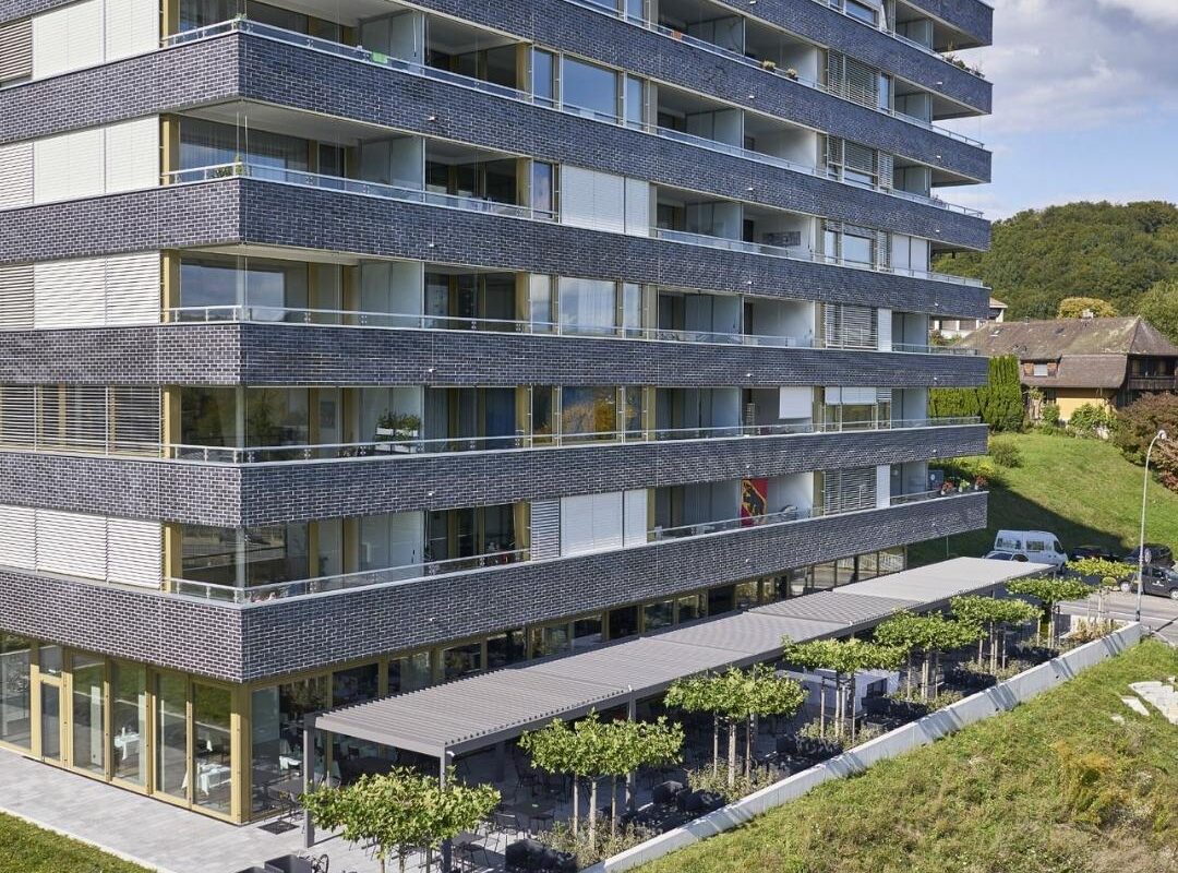 Modernes Wohngebäude in Hinterkappelen Bern mit grossflächigem SKL 100 Lamellendach über der Terrasse und integriertem Sitzbereich.