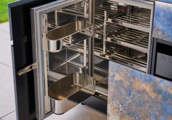 Detailaufnahme des modularen Innenausbaus einer Avers Outdoor-Küche mit Chromstahlregalen und verstellbaren Tablaren.