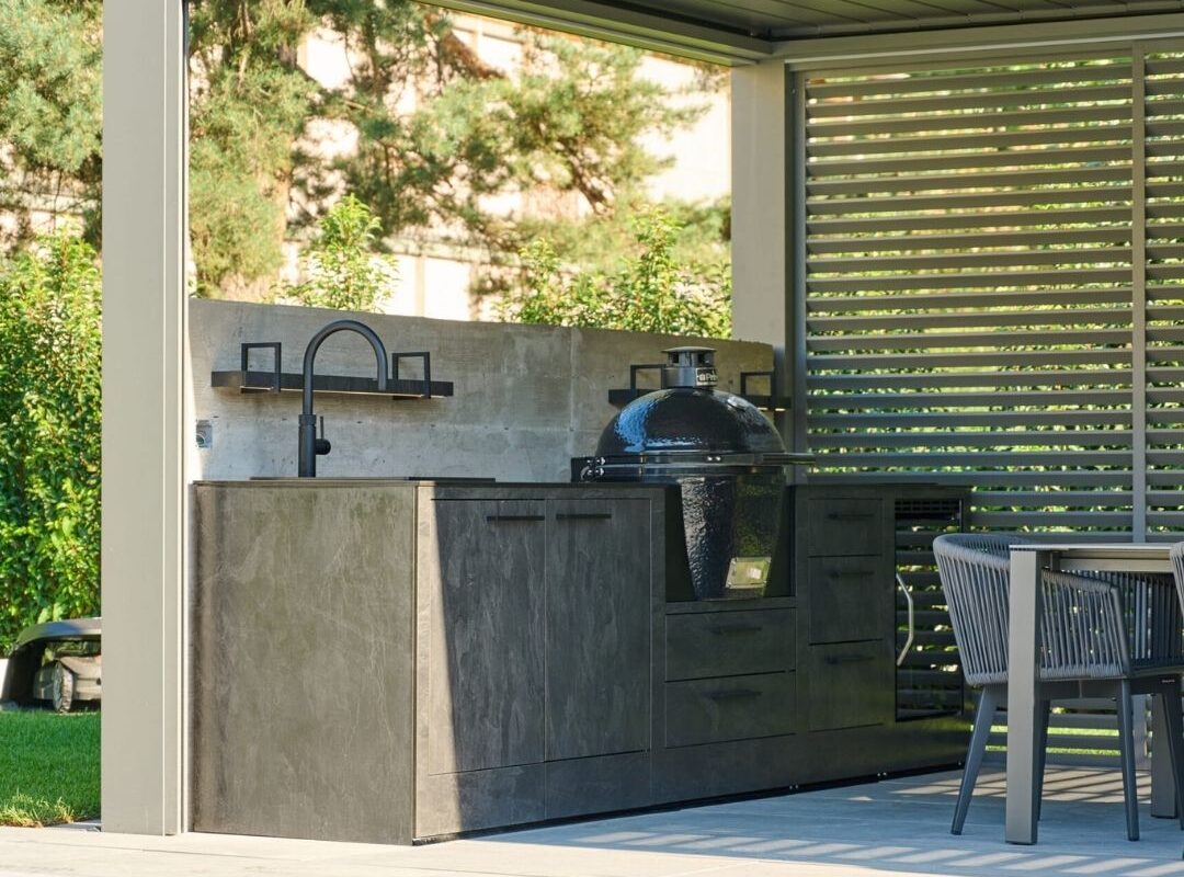 Outdoor-Küche mit Grill und Spüle unter einem modernen Lamellendach, direkt am Poolbereich in Münchenstein (BL).