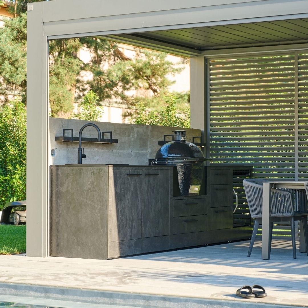 Outdoor-Küche mit Grill und Spüle unter einem modernen Lamellendach, direkt am Poolbereich in Münchenstein (BL).