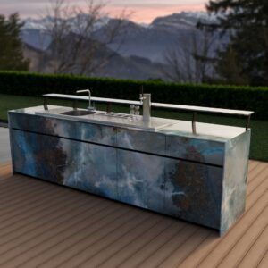 Exklusive Theiss Outdoor-Bar mit Zapfanlage, Spülbecken und modernem Design in blauen Steinfronten vor Alpenkulisse bei Sonnenuntergang.