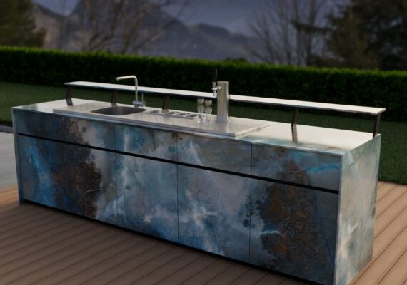 Exklusive Theiss Outdoor-Bar mit Zapfanlage, Spülbecken und modernem Design in blauen Steinfronten vor Alpenkulisse bei Sonnenuntergang.
