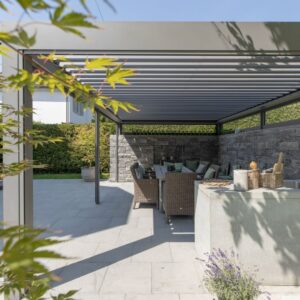 Moderne Pergola mit Lamellendach, harmonisch in eine puristische Architektur mit Natursteinmauer und Garten integriert.