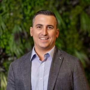 Portrait des CEO von Thermogreen im Anzug vor grünem Hintergrund.