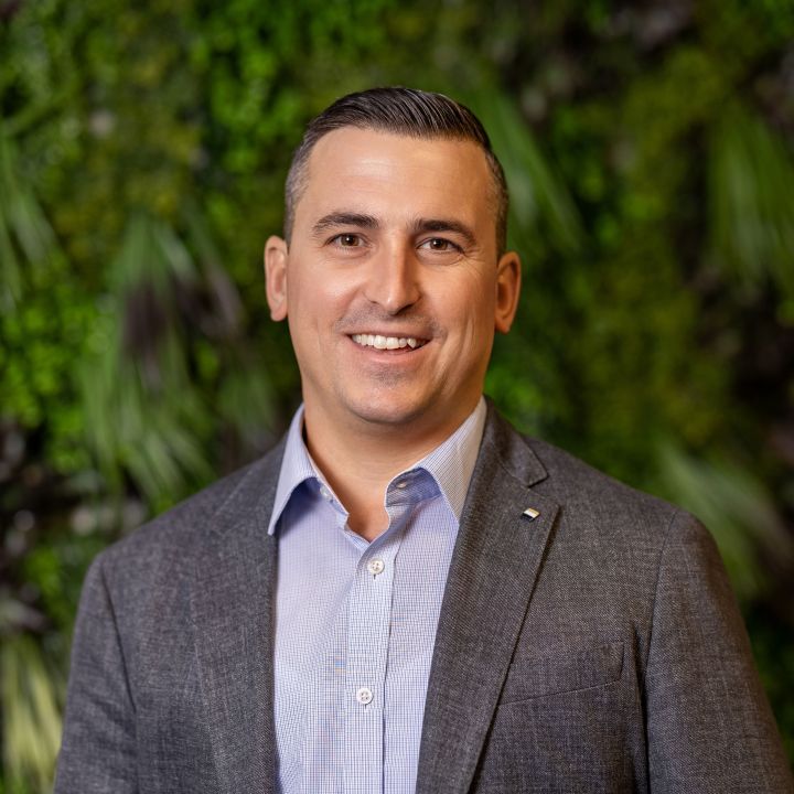 Portrait des CEO von Thermogreen im Anzug vor grünem Hintergrund.