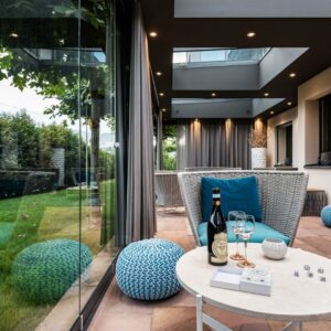 Moderner Wintergarten mit Glaswänden, eleganter Lounge und stimmungsvoller LED-Beleuchtung.