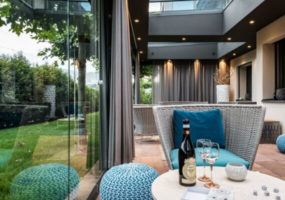 Moderner Wintergarten mit Glaswänden, eleganter Lounge und stimmungsvoller LED-Beleuchtung.