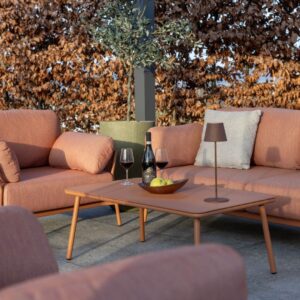 Elegante Outdoor Lounge mit terrakottafarbenen Sofas, Couchtisch mit Rotwein und Schale Äpfel, im modernen Aussenbereich von Nook.