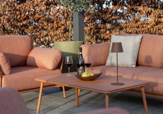 Elegante Outdoor Lounge mit terrakottafarbenen Sofas, Couchtisch mit Rotwein und Schale Äpfel, im modernen Aussenbereich von Nook.