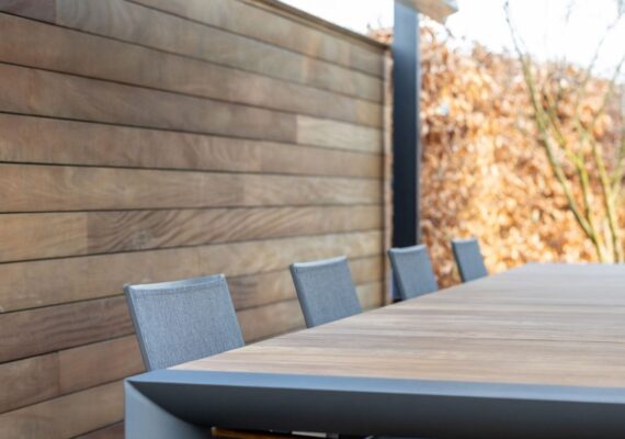Moderner Outdoor-Esstisch mit Holzplatte und grauen Stühlen im stilvollen Aussenbereich.
