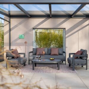 Elegante Nook Outdoor-Lounge in Grau mit passenden Sesseln, Couchtisch und Accessoires unter einem Glasdach.