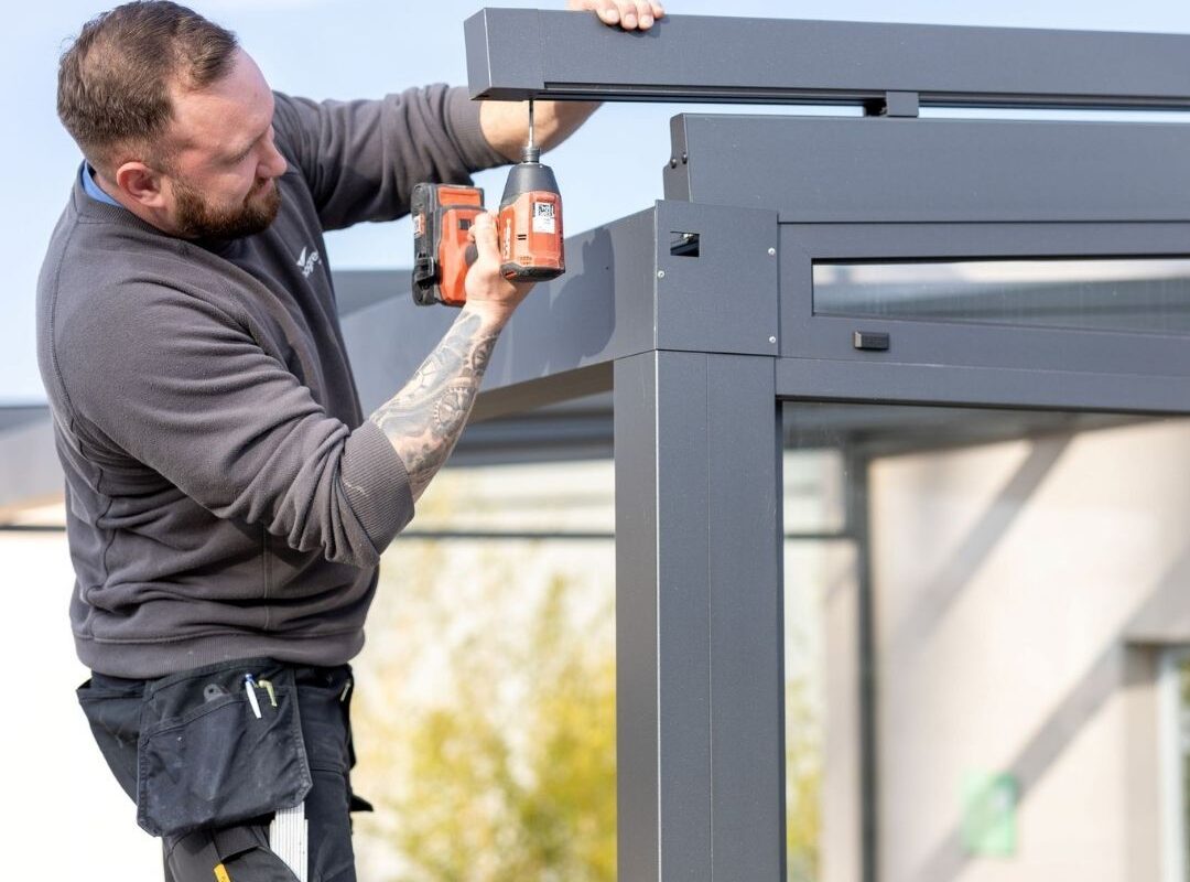 Thermogreen Monteur montiert eine Aluminium-Überdachung mit professionellem Werkzeug.