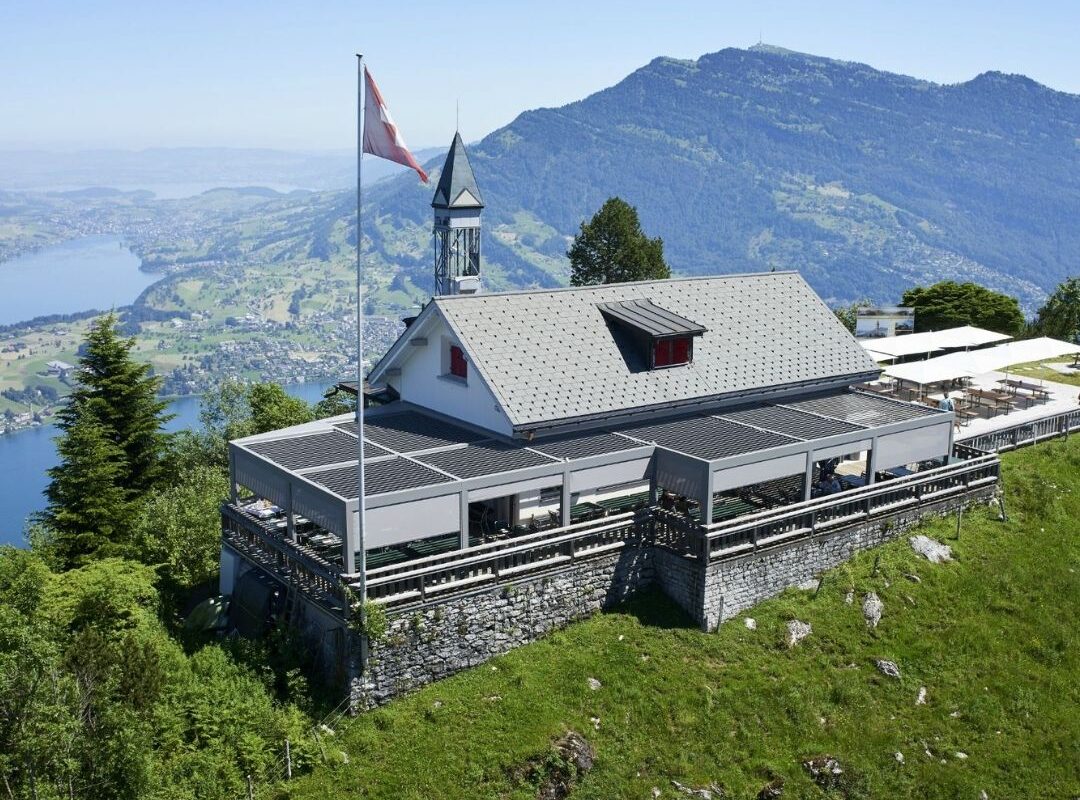 Restaurantterrasse in den Schweizer Bergen mit grossflächigen Lamellendächern, die Gäste vor Sonne und Wetter schützen.