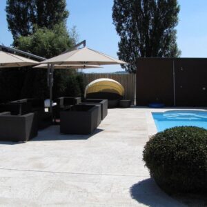 Zwei elegante Sonnenschirme spenden Schatten über einer modernen Lounge am Pool mit stilvollen Rattanmöbeln.