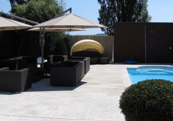 Zwei elegante Sonnenschirme spenden Schatten über einer modernen Lounge am Pool mit stilvollen Rattanmöbeln.