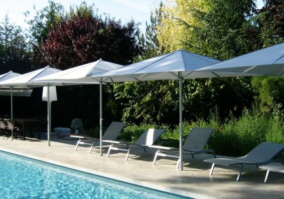 Reihe moderner Sonnenschirme am Pool mit Liegestühlen in eleganter Anordnung.