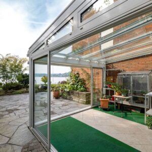 Glasdach mit Glaswänden als Wintergartenlösung an einem Wohnhaus mit Blick in den Garten.