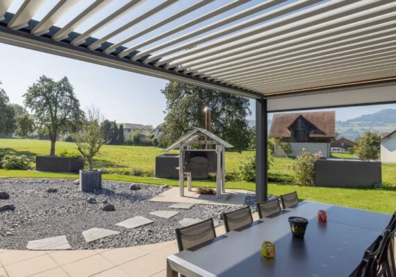 Lamellendach mit grossem Esstisch und Blick in den Garten, moderne Überdachung für gesellige Stunden im Freien.