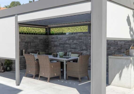 Lamellendach mit integrierten Seitenmarkisen als flexibler Sonnenschutz über einer Terrasse mit Esstisch und Gartenstühlen.