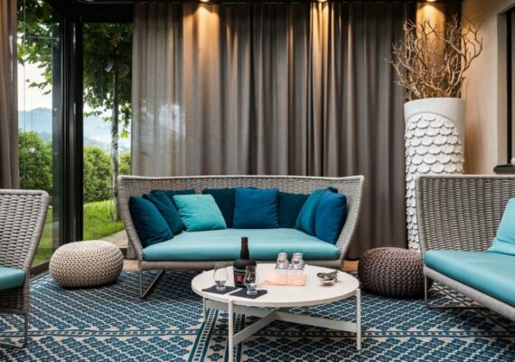 Eleganter Wintergarten mit modernen Loungemöbeln, Teppich und stimmungsvoller Beleuchtung.