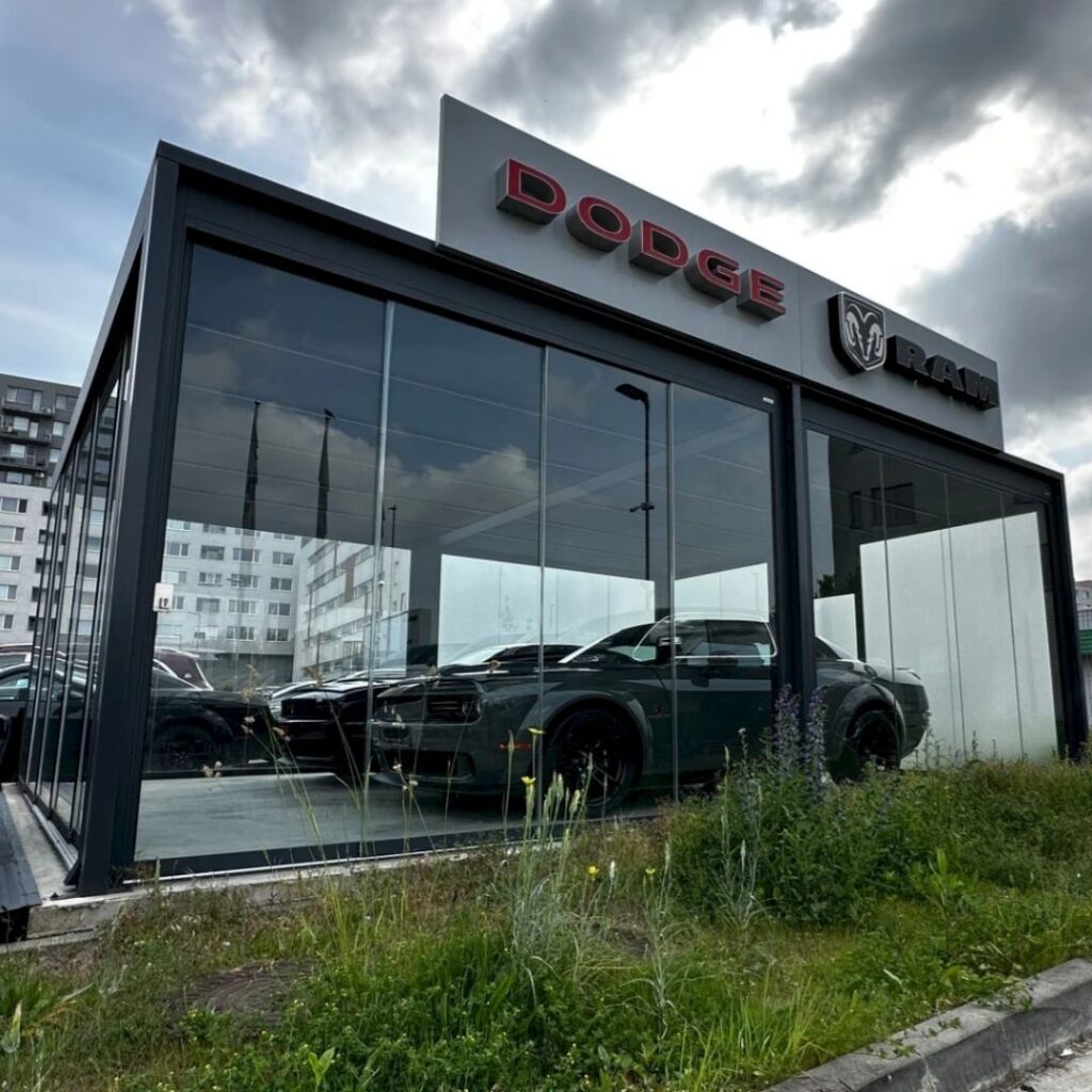 Exklusiver Carport mit Glaswänden für Dodge und RAM Fahrzeuge – modernes Design, Schutz und Premium-Präsentation.