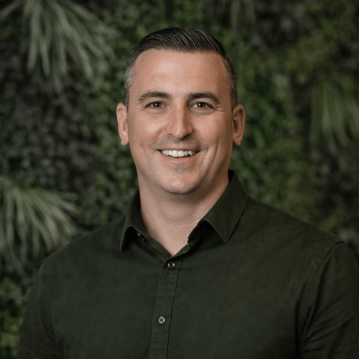 Portrait des CEO von Thermogreen im Anzug vor grünem Hintergrund.