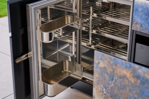 Detailaufnahme des modularen Innenausbaus einer Avers Outdoor-Küche mit Chromstahlregalen und verstellbaren Tablaren.