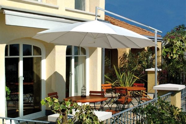 Weisser DACAPO Sonnenschirm mit seitlichem Mast auf einer sonnigen Haus-Terrasse mit Holzmöbeln.