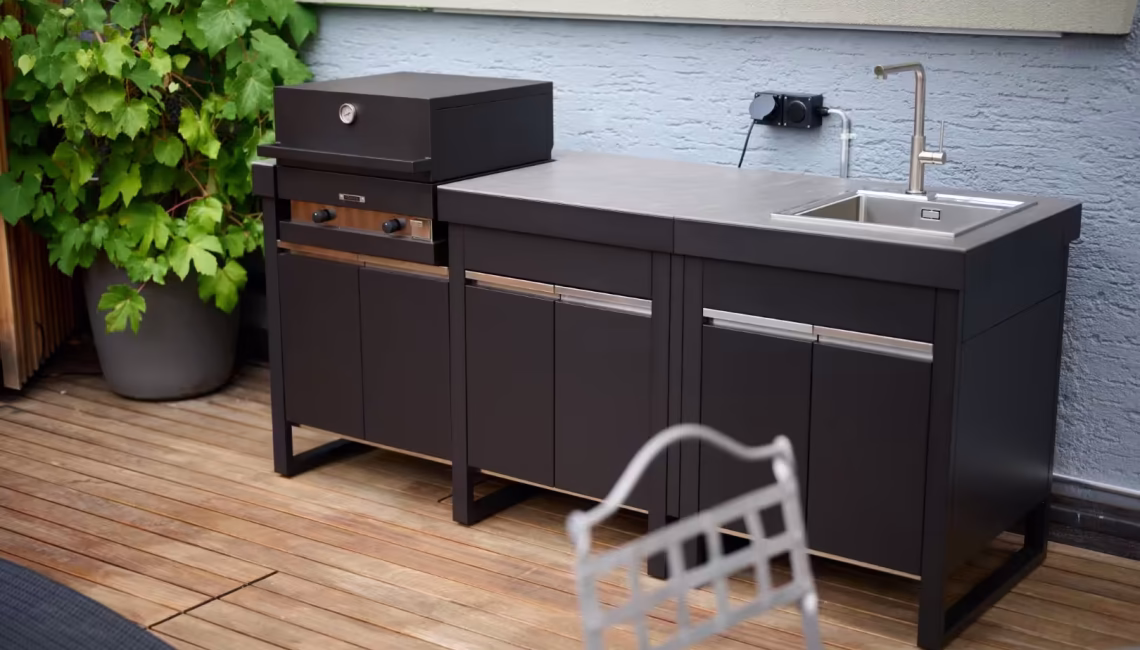 Aussenküche mit geschlossenem Grillmodul und integriertem Spülbecken auf Holzterrasse