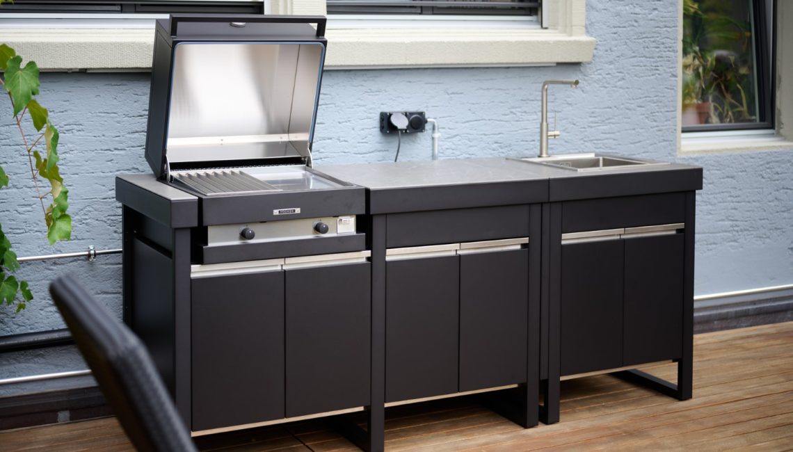 Fogher Lares Aussenküche mit geöffnetem Grill und integriertem Spülbecken auf Holzterrasse in Zürich