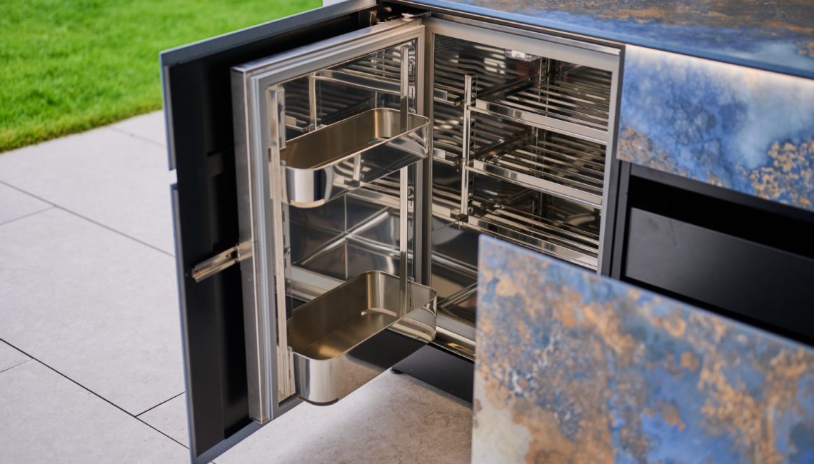 Integrierter Edelstahl-Kühlschrank in Aussenküche mit geöffneter Tür und Innenausstattung
