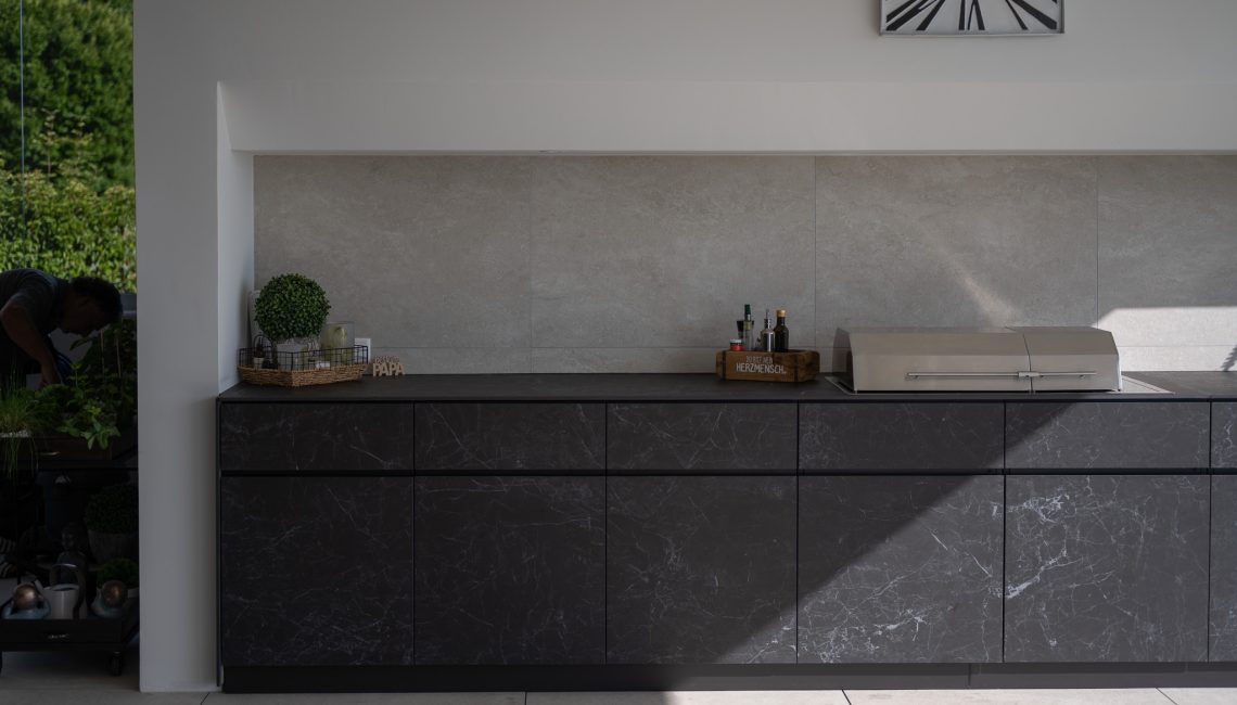 Frontansicht der Outdoor Küche Theiss Avers in Keramik Nero Greco mit geschlossenem Grill auf moderner Terrasse in Widen