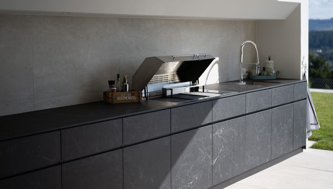 Moderne Aussenküche Theiss Avers in Keramik Nero Greco mit integriertem Elektro Grill und Spülbecken auf einer privaten Terrasse in Widen