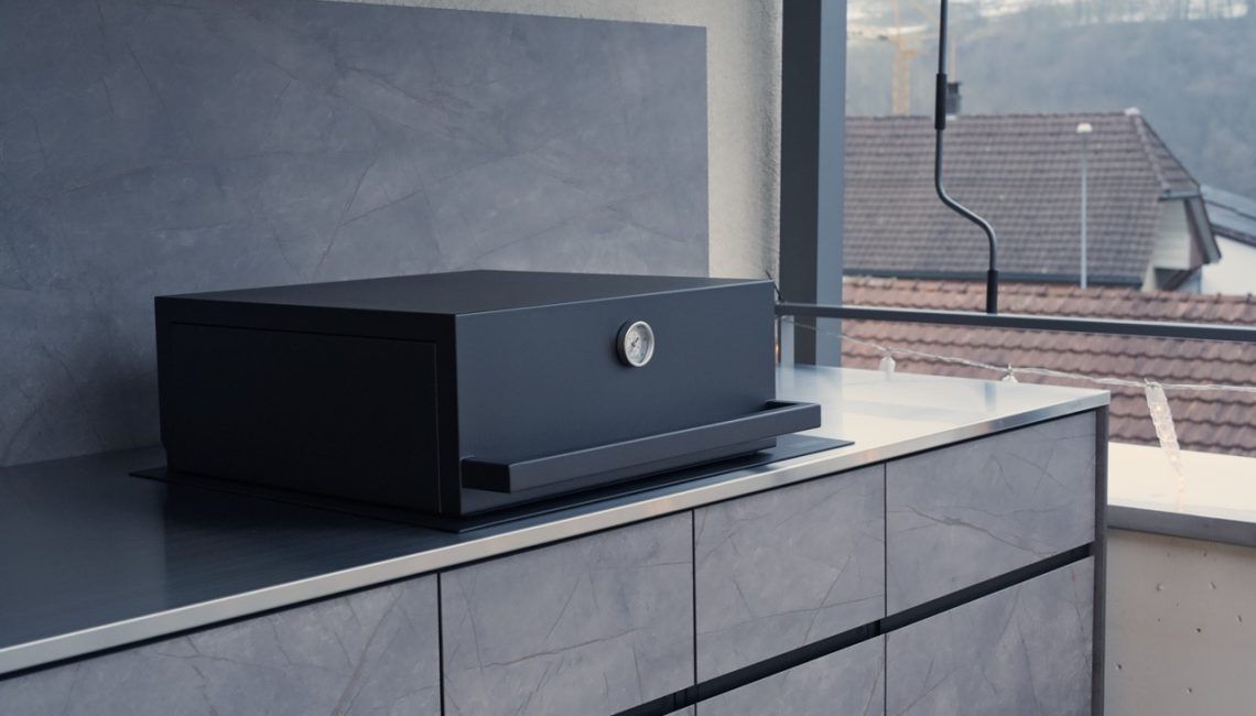 Aussenküche mit Edelstahl-Arbeitsfläche, Grill und Rückwand unter Überdachung