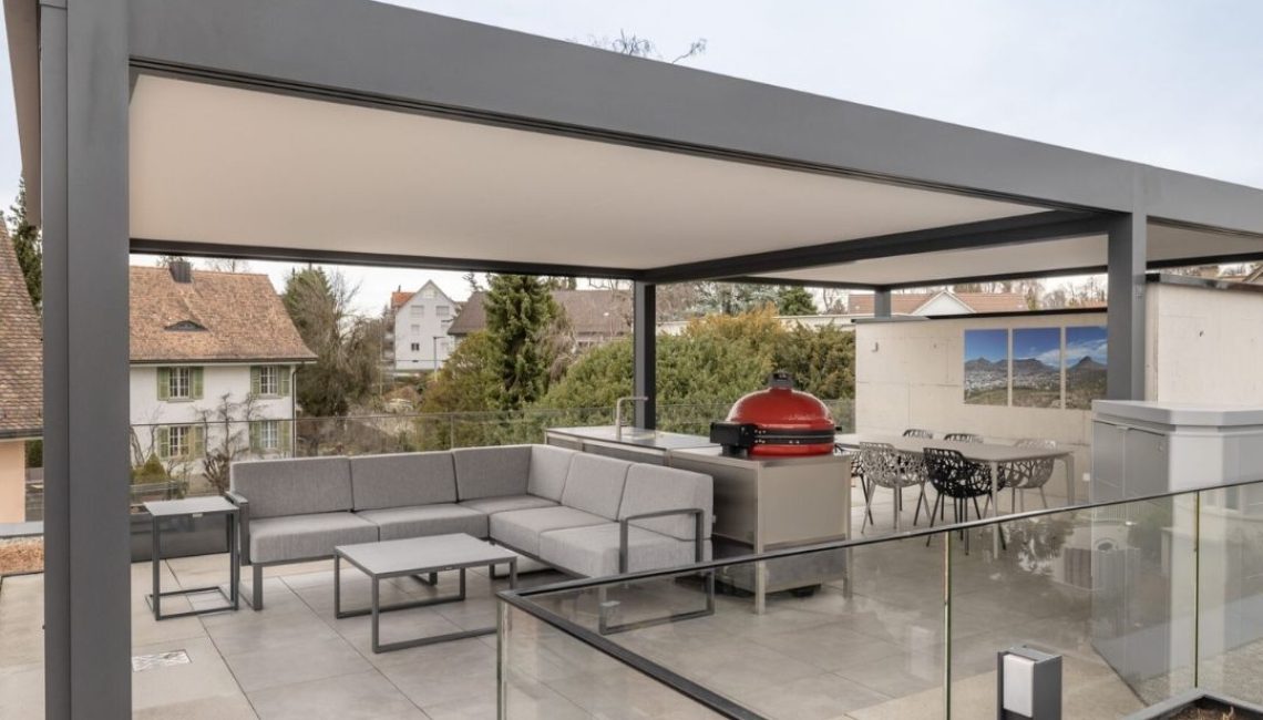Modernes Festdach ECL 130 auf einer Attikaterrasse mit Lounge, Outdoor-Küche und Esstisch.