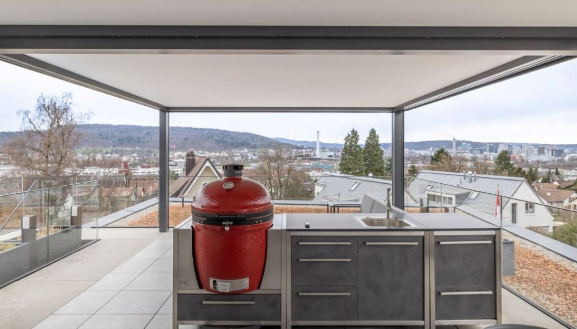 Festdach ECL 130 mit integrierter Outdoor-Küche und rotem Keramikgrill auf einer Attikaterrasse in Wallisellen, Zürich.