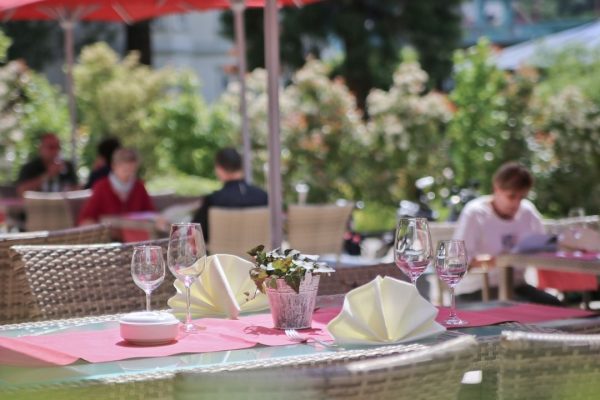 Rote FILIUS Sonnenschirme auf einer eingedeckten Restaurantterrasse, stilvoller Sonnenschutz und stimmungsvolle Atmosphäre.