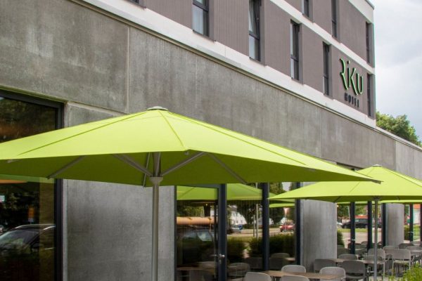 FILIUS Sonnenschirme in frischem Grün vor einem Hotel, eleganter und funktionaler Sonnenschutz für Gastronomie- und Aussenbereiche.