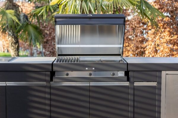 FOGHER Outdoor-Küche mit geöffnetem Grill im modernen Design, eingebaut in eine elegante Küchenzeile im Garten.