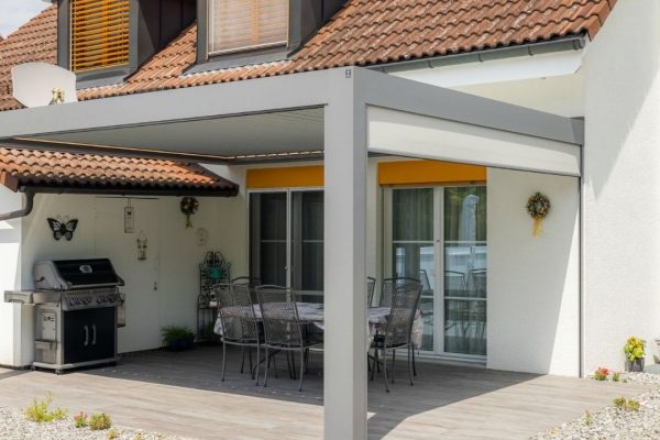 SKL 140 Lamellendach an einem Einfamilienhaus, harmonisch an die Terrasse angebaut und mit seitlichem Screen ausgestattet.