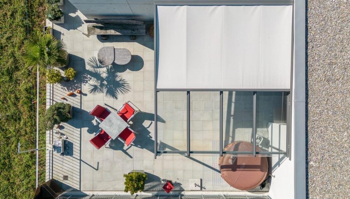 Terrasse mit Glasdach und Beschattung aus der Vogelperspektive – moderner Outdoor-Bereich mit Sitzgruppe, Pflanzen und Whirlpool.