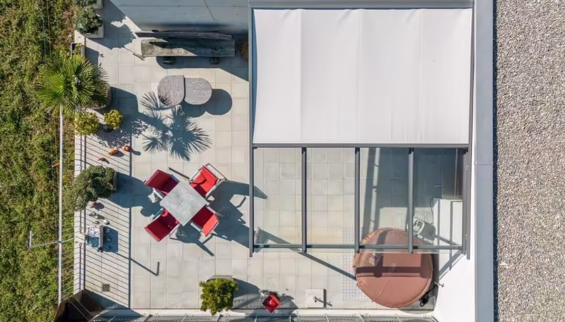 Terrasse mit Glasdach und Beschattung aus der Vogelperspektive – moderner Outdoor-Bereich mit Sitzgruppe, Pflanzen und Whirlpool.