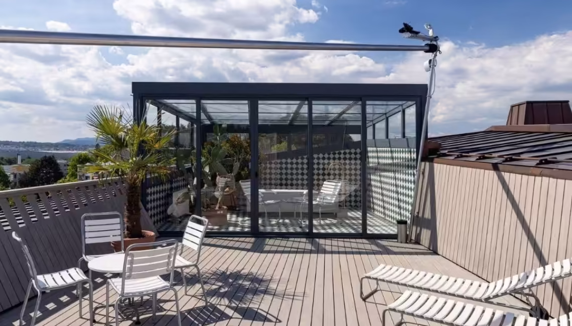 Glasdach-Wintergarten auf dem Dachgarten des Projekts «Kloten-Milano» mit Sitzgelegenheiten und Palmen, ausgelegt für Schneelasten bis 380 kg/m².