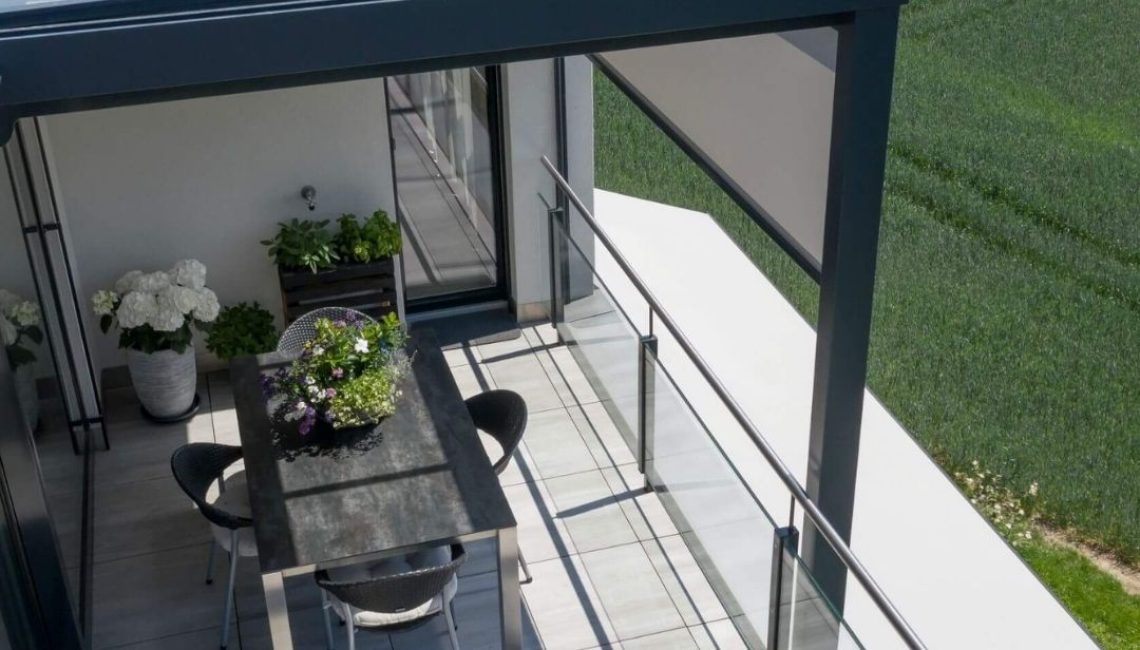 Modernes Glasdach auf einer Terrasse in Uitikon Waldegg mit Esstisch, Stühlen und Pflanzen, umgeben von freier Natur.