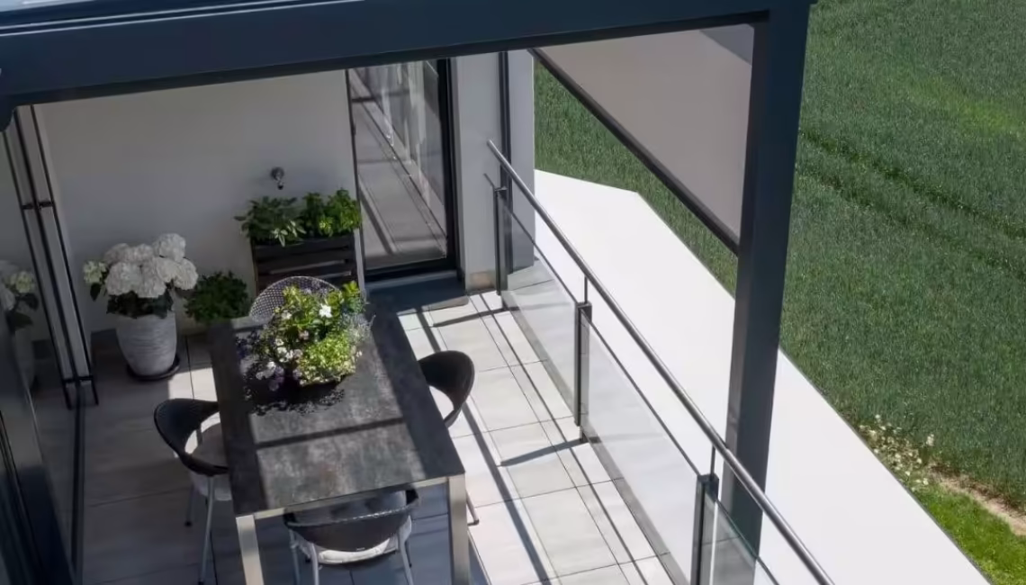 Modernes Glasdach auf einer Terrasse in Uitikon Waldegg mit Esstisch, Stühlen und Pflanzen, umgeben von freier Natur.